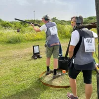 Two shooters on a meadow, one in a ring calling for pull